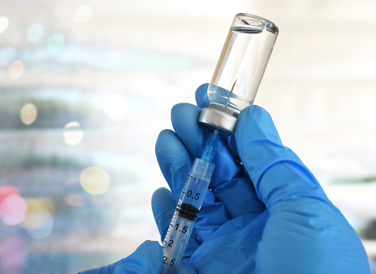 Gloved hand holding syringe and vial